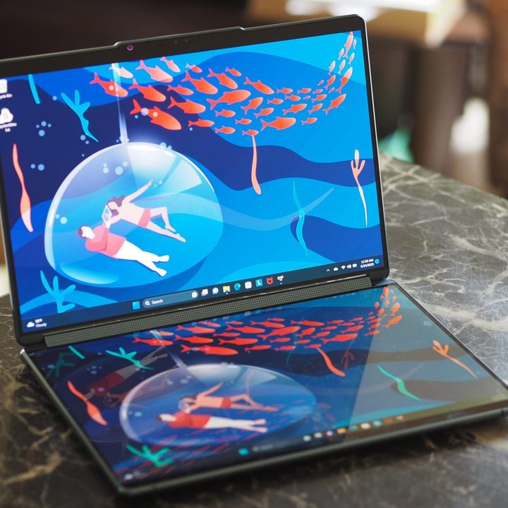 The two screens of the Yoga Book 9i open on a table.