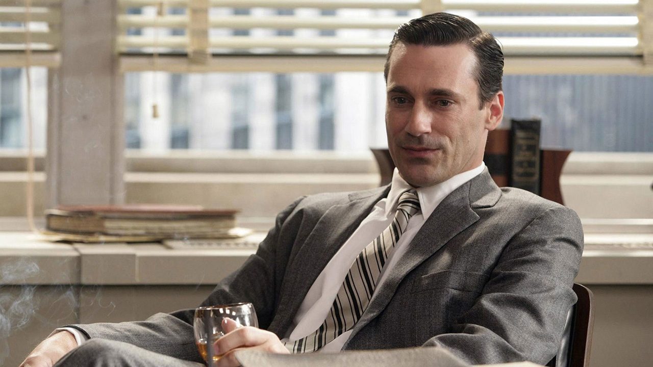 Don Draper from Mad Men sitting in his office having a drink.