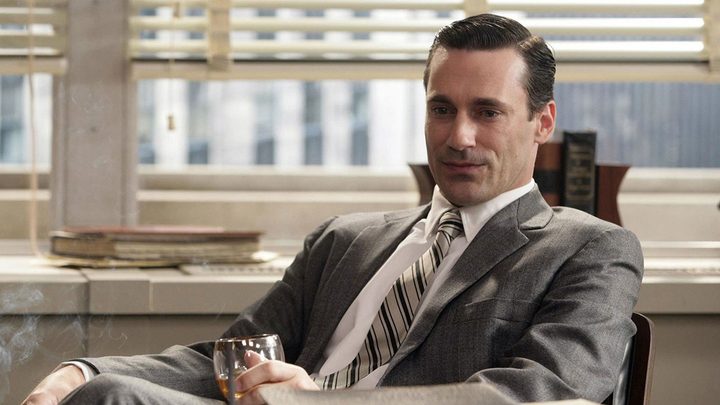 Don Draper from Mad Men sitting in his office having a drink.