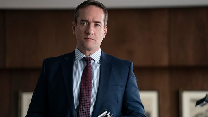 Tom wearing a suit looking at someone in a scene from Succession.