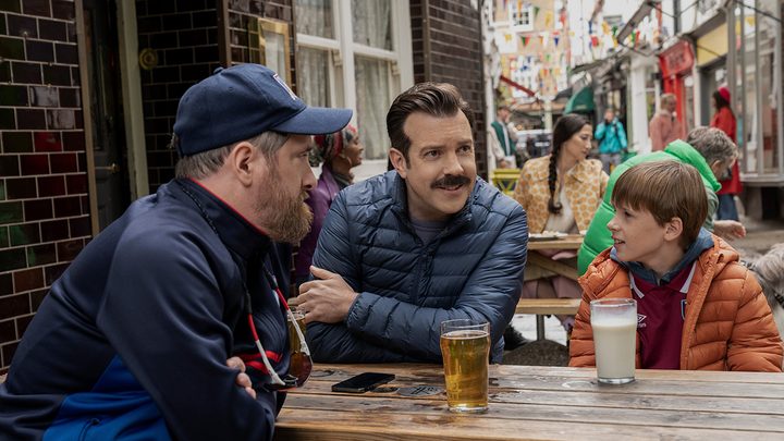 Coach Beard, Ted, and Henry sitting on a patio in a scene from Ted Lasso.