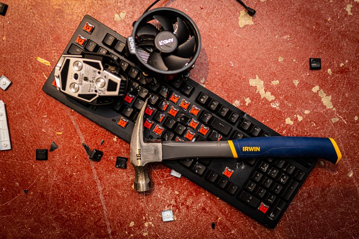 A broken keyboard and hammer among several PC components.