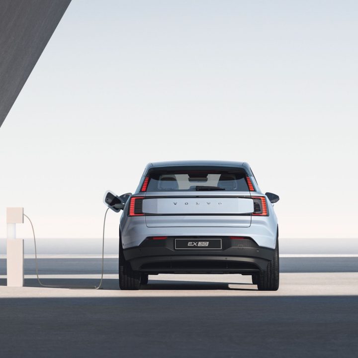 A 2025 Volvo EX30 from the rear as it it plugged into a charger.