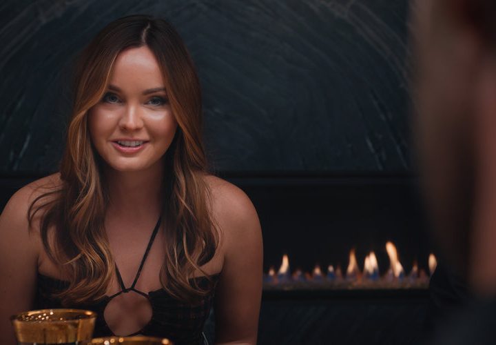 A woman sits at the table and smiles in Based on a True Story.