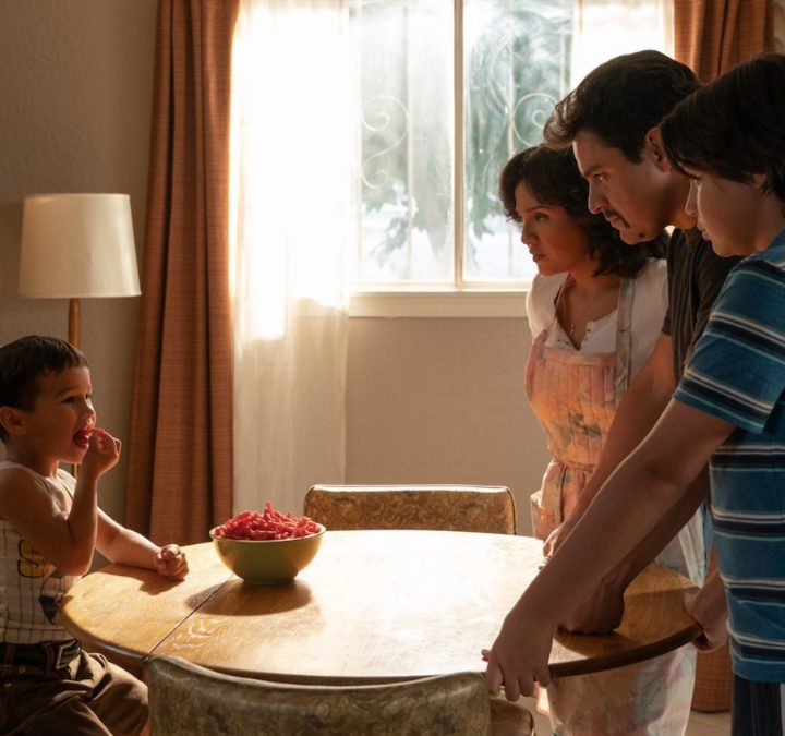 A family gathers around a table to watch a boy eat cheetos in Flamin' Hot.