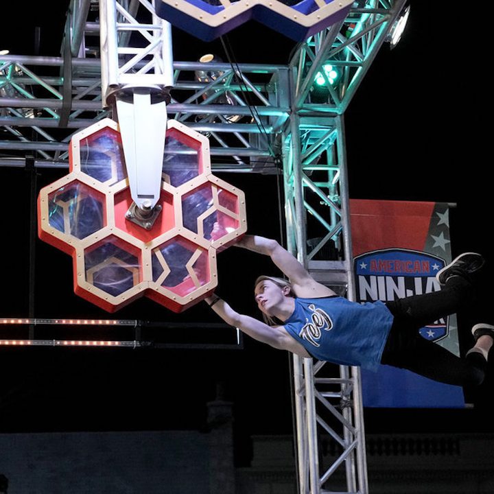 A woman holds onto an obstacle in American Ninja Warrior.