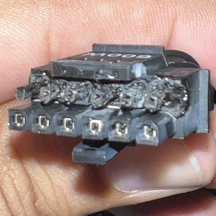 A person holds the connectors of an Nvidia 12VHPWR cable from an RTX 4090 graphics card. The ends of the connectors are burned and melted from where the cable has overheated.