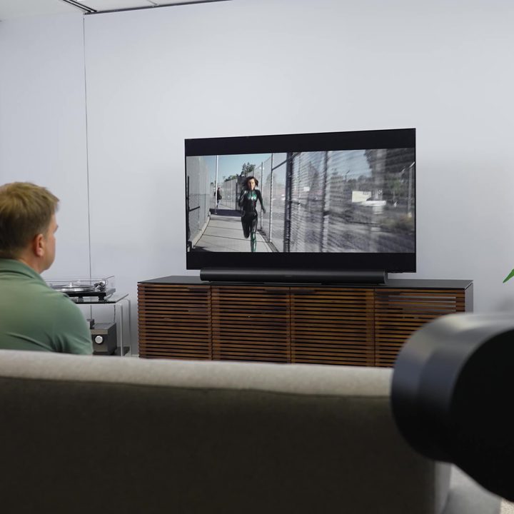 A man watches a movie in a studio with a Sonos Era 300 in a surround sound setup.