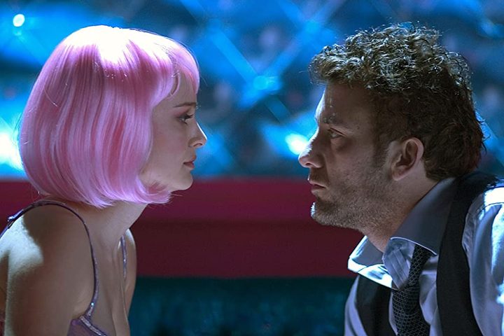 A woman in a pink wig looks at a man in Closer.