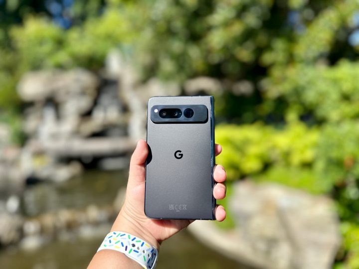Google Pixel Fold in Obsidian in hand in front of snow white fountain.