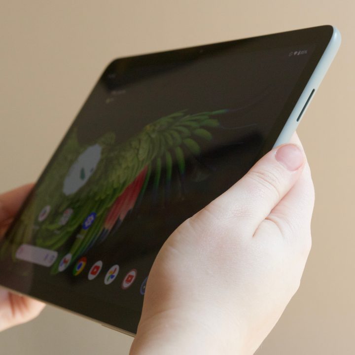 Someone holding the Google Pixel Tablet with the display turned on.