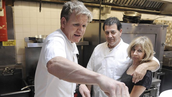 Chef Gordon Ramsay in the kitchen of a restaurant with a couple on Kitchen Nightmares.