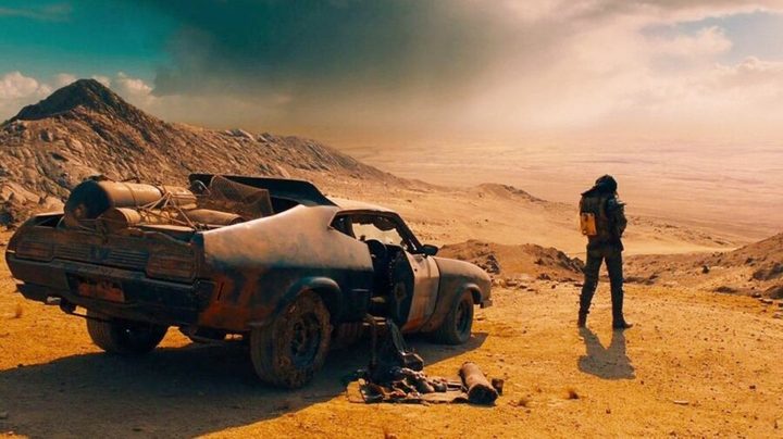 A man stands in front of his car in Mad Max: Fury Road.