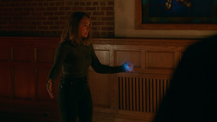 Angelina holding out her hands, the sapphire glowing in a scene from Manifest.