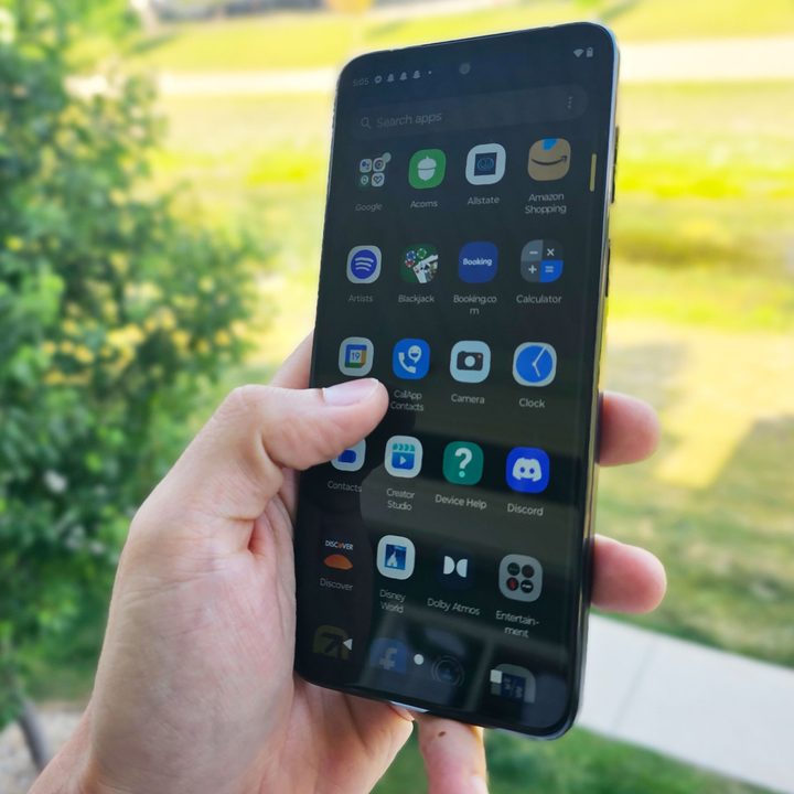 The Moto G 5G held in a hand with its screen illuminated as someone scrolls.