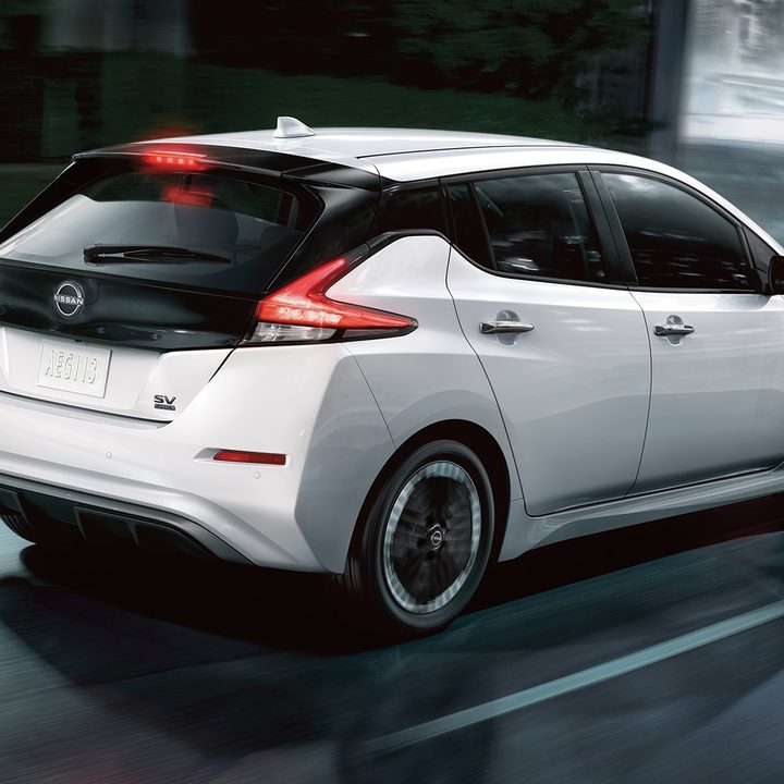 A 2023 Nissan Leaf on a rainy urban road.