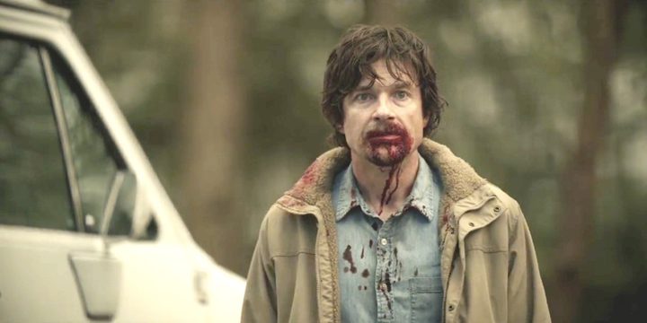 A man stands with a bloody nose in The Outsider.