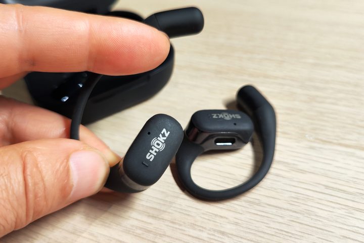Hand holding a Shokz OpenFit earbud.