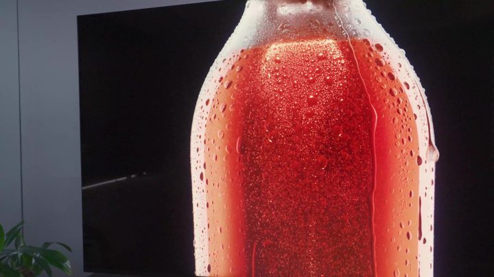 Beads of condensation on a glass bottle containing red liquid on a TCL QM8.