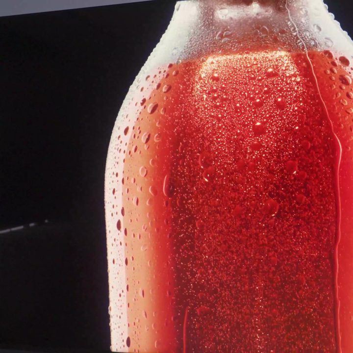 Beads of condensation on a glass bottle containing red liquid on a TCL QM8.