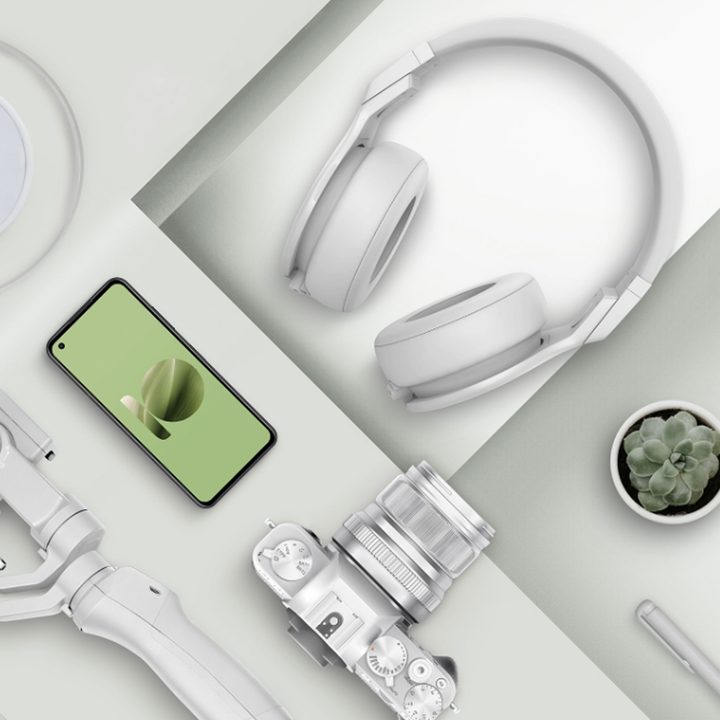 An image of the ZenFone 10 laying on a table arranged next to some phone accessories like headphones and chargers.