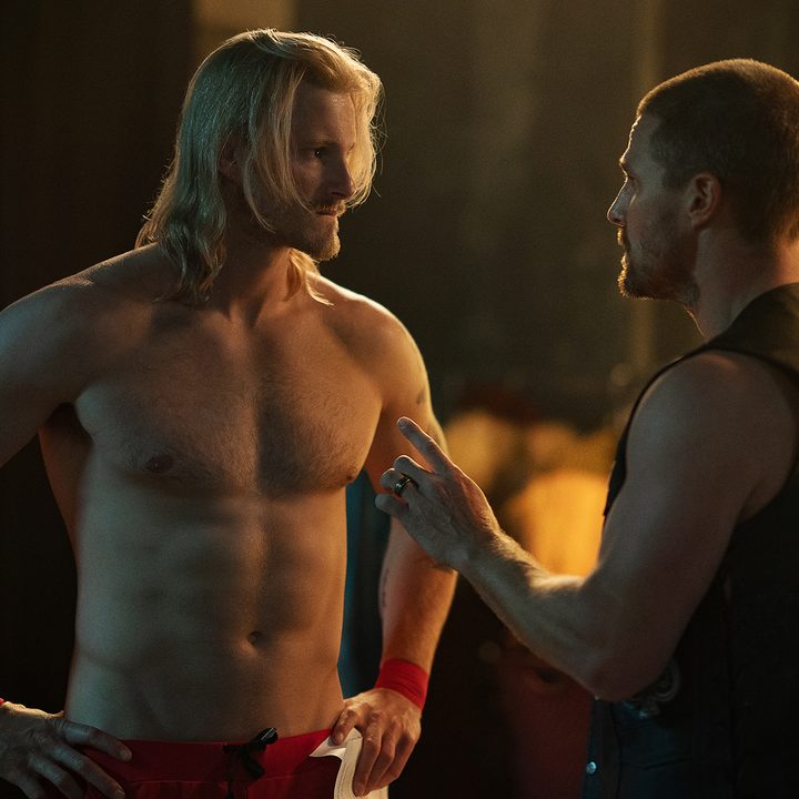 Alexander Ludwig stands and faces Stephen Amell in Heels.