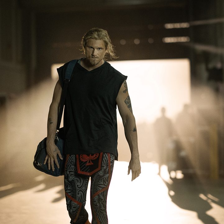 Alexander Lugwig walks forward holding a bag over shoulder in Heels.