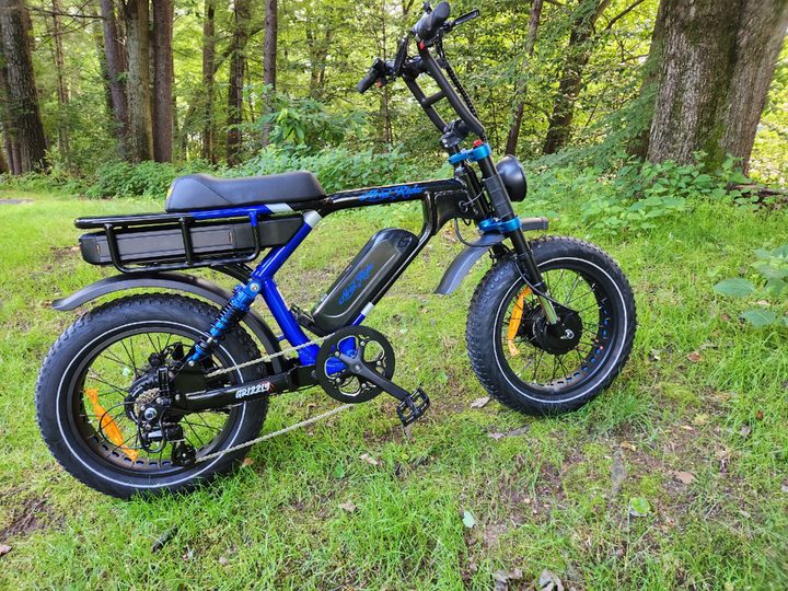 Ariel Rider Grizzly full on right side parked on a slight incline with trees in the background.