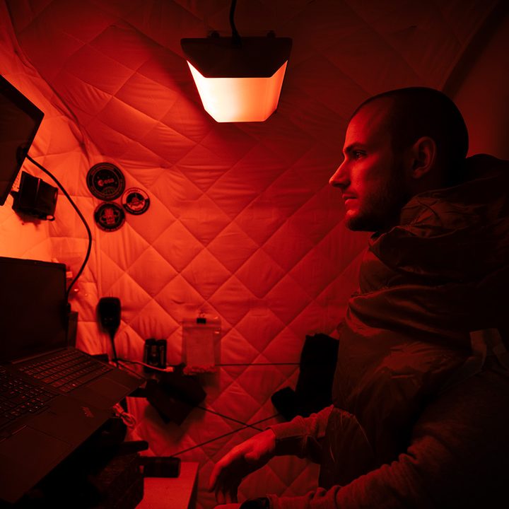 A man in a small room with a Circadian Light glowing red.