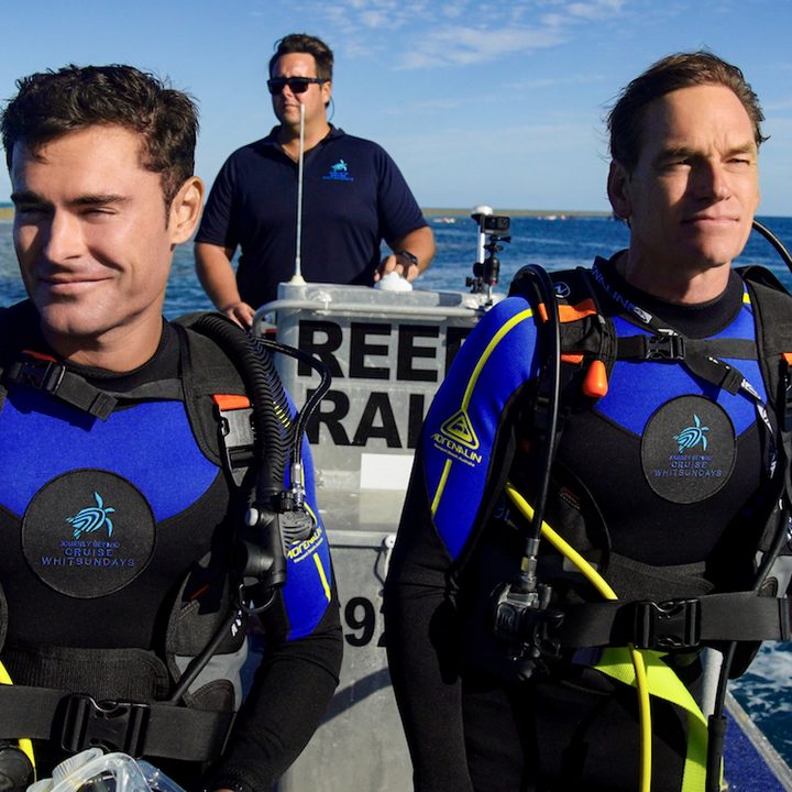 Two men prepare to scuba dive in Down to Earth with Zac Efron.