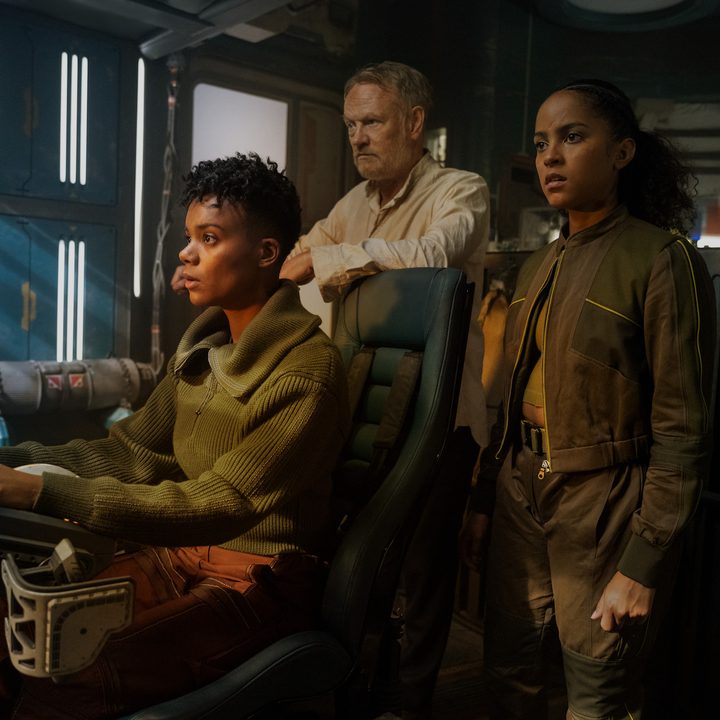 One character pilots a ship as two characters stand behind in Foundation.