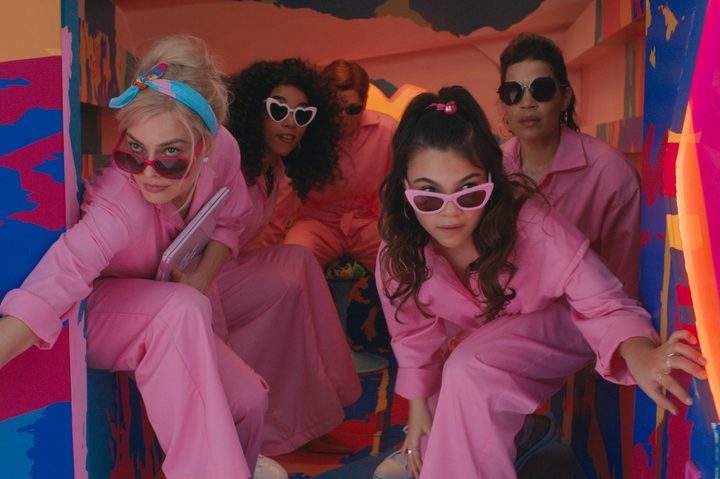 Margot Robbie and Ariana Greenblatt look out the back doors of a truck in Barbie.