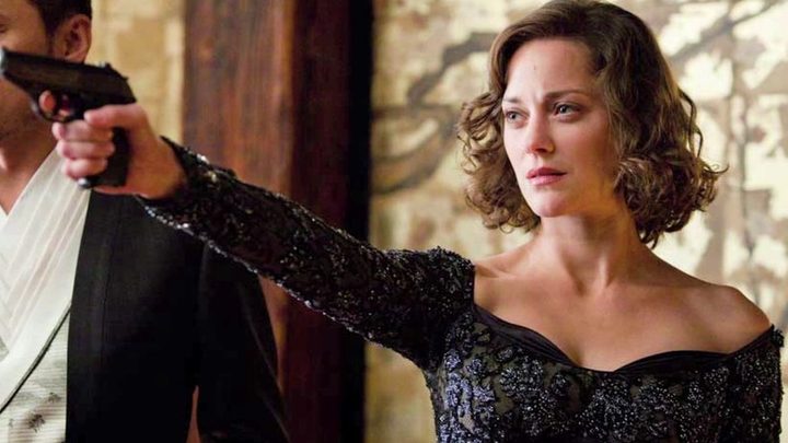 Marion Cotillard as Mal aiming a gun at someone off-camera in Inception.