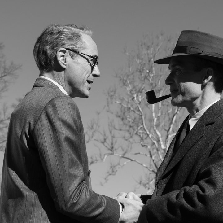 Robert Downey Jr. and Cillian Murphy as Lewis Strauss and Robert J. Oppenheimer shaking hands in black-and-white in Oppenheimer.