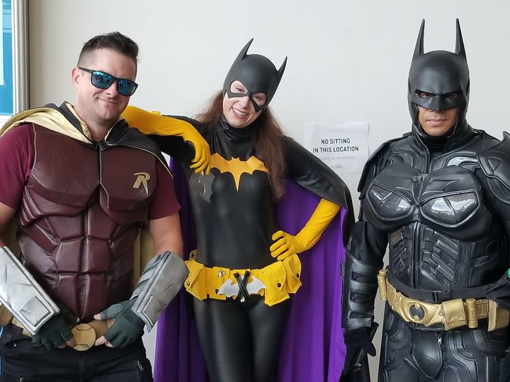 Fans dressed as Robin, Batgirl, and Batman at Comic-Con.
