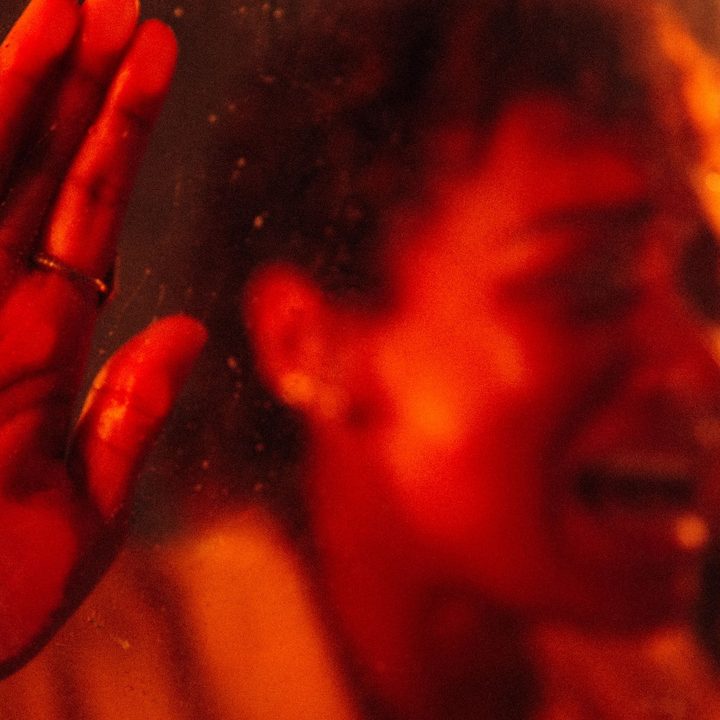 Sophie Wilde bangs on a car window from the inside, bathed in red light.