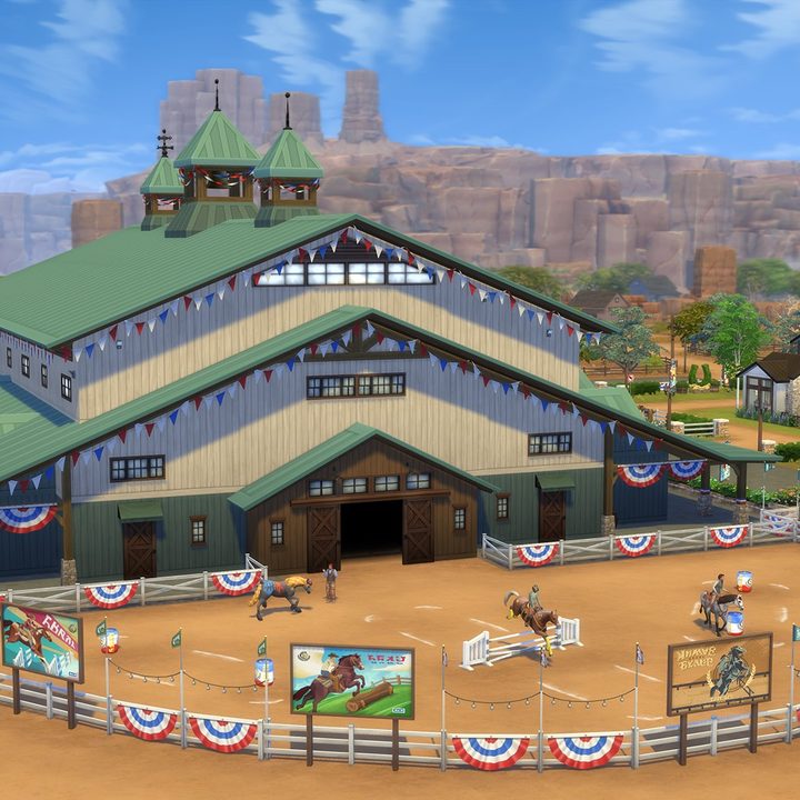 A full shot of the equestrian center in The Sims 4: Horse Ranch. It's a large white building with a green root and stable doors. A fenced in riding arena is out front.