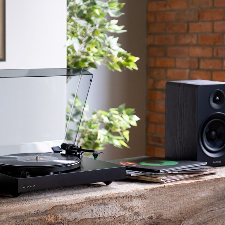 The Fluance RT81+ Elite turntable in the black finish with a speaker on a table.