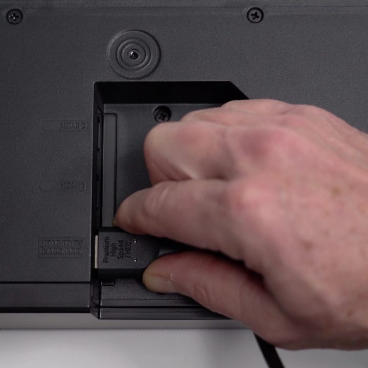 A man's hand inserting a cable into the HDMI ARC port on the back of a TV.