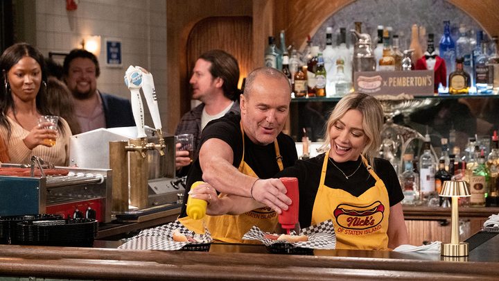 Sophie and her father Nick dressing hot dogs in a scene from How I Met Your Father.