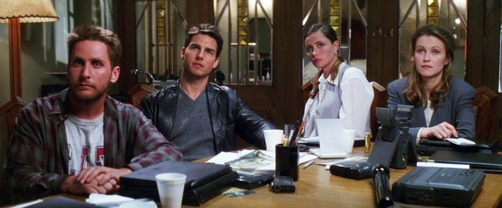 Four people sit at a table in Mission: Impossible.