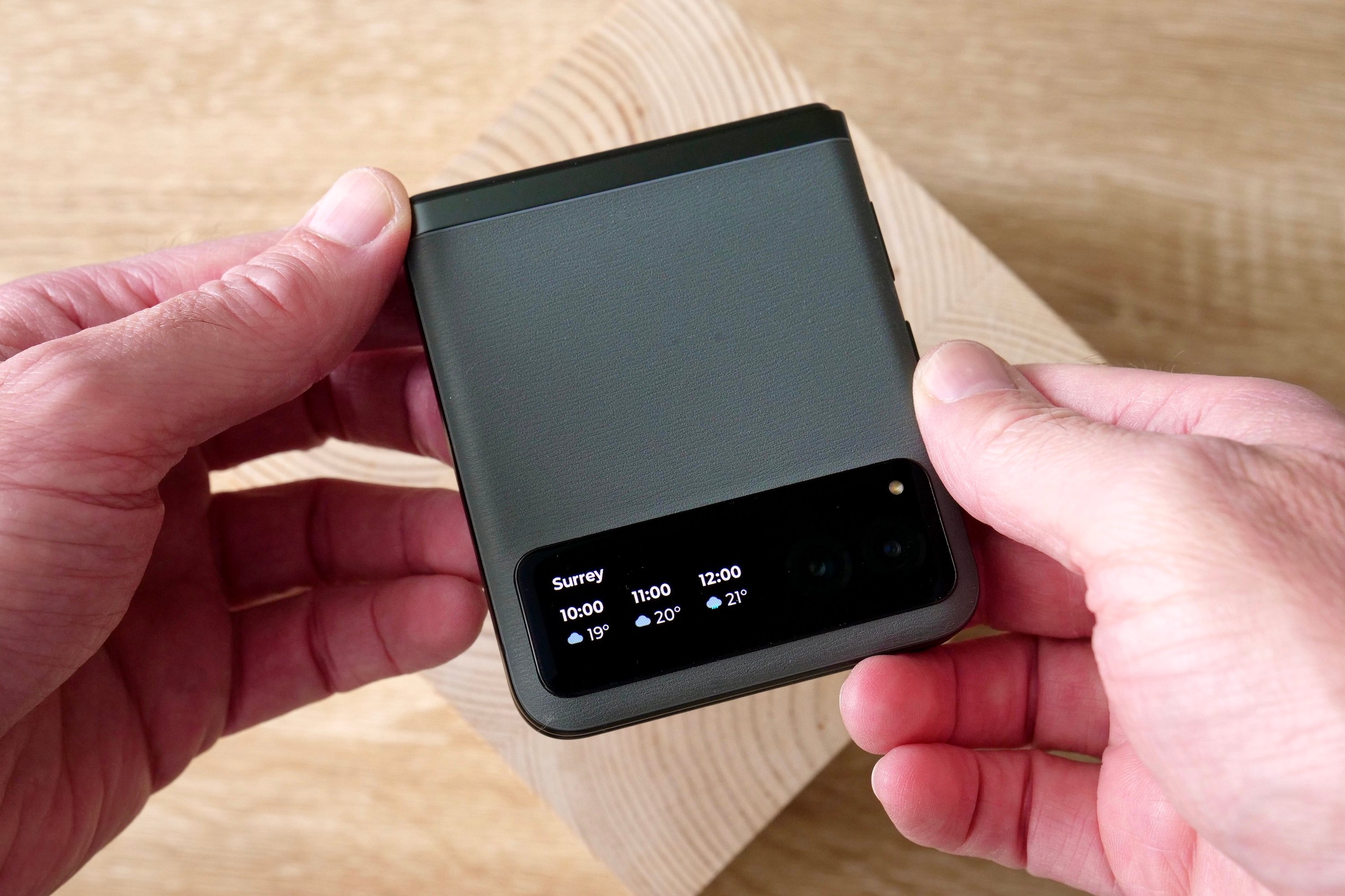 A person holding the Motorola Razr 40, showing the weather widget.