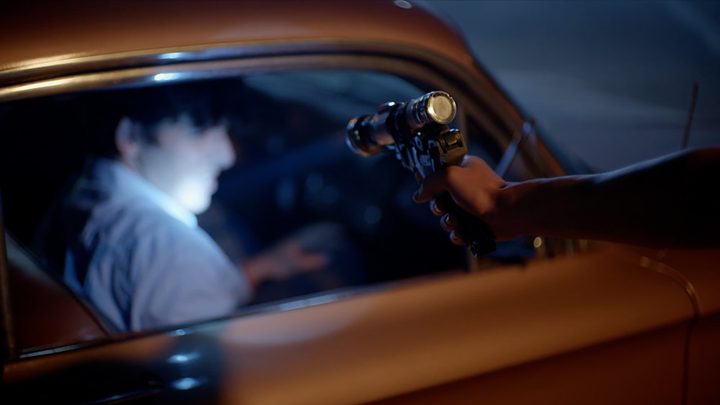A man recoils in a car, a shooter approaches in a reenactment scene from Myth of the Zodiac Killer.