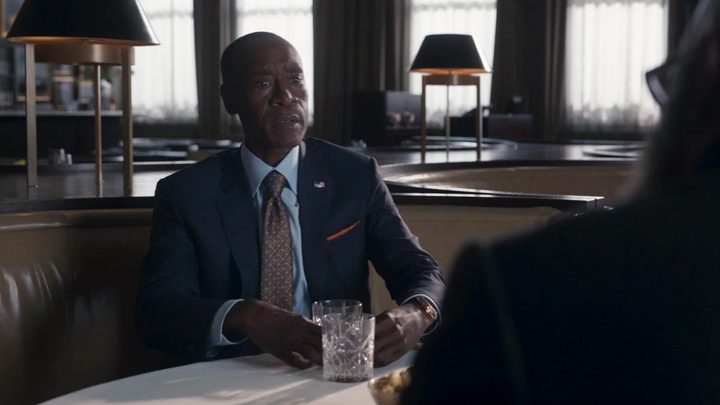 Rhodey sitting at a table in a suit in Secret Invasion.