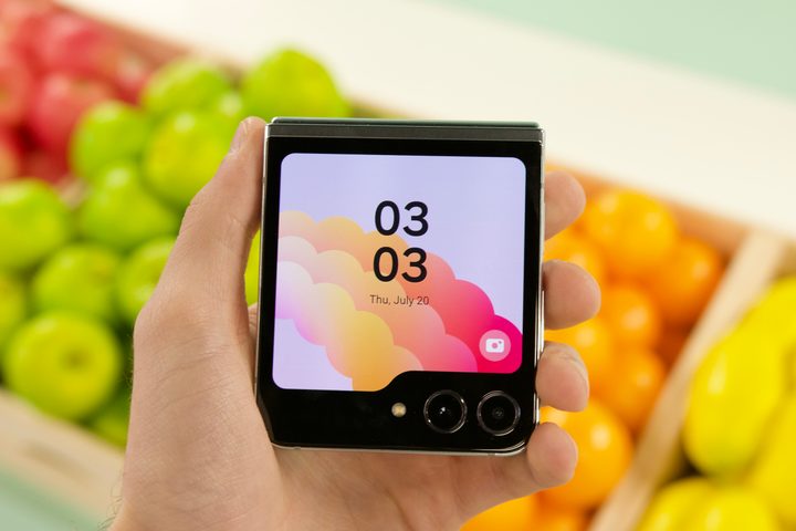 Holding the Samsung Galaxy Z Flip 5 with its cover screen on.