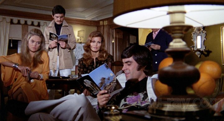 A man reads a book while people watch in The Last of Shelia.