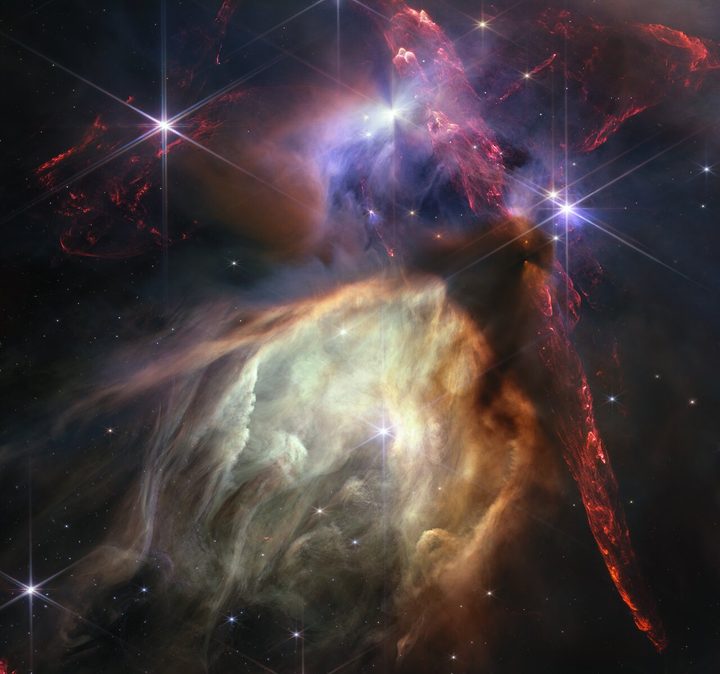 The first anniversary image from the NASA/ESA/CSA James Webb Space Telescope displays star birth like it’s never been seen before, full of detailed, impressionistic texture. The subject is the Rho Ophiuchi cloud complex, the closest star-forming region to Earth. It is a relatively small, quiet stellar nursery, but you’d never know it from Webb’s chaotic close-up. Jets bursting from young stars crisscross the image, impacting the surrounding interstellar gas and lighting up molecular hydrogen, shown in red. Some stars display the telltale shadow of a circumstellar disc, the makings of future planetary systems.