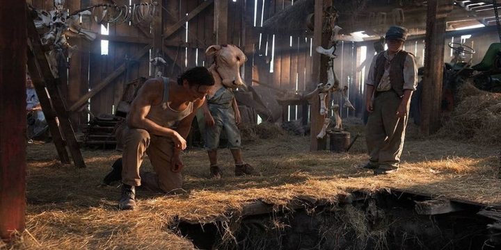 A young Leatherface wears a cow head and stares down a pit