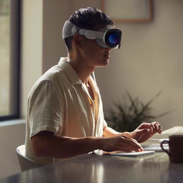Apple Vision Pro being worn by a person while using a keyboard.