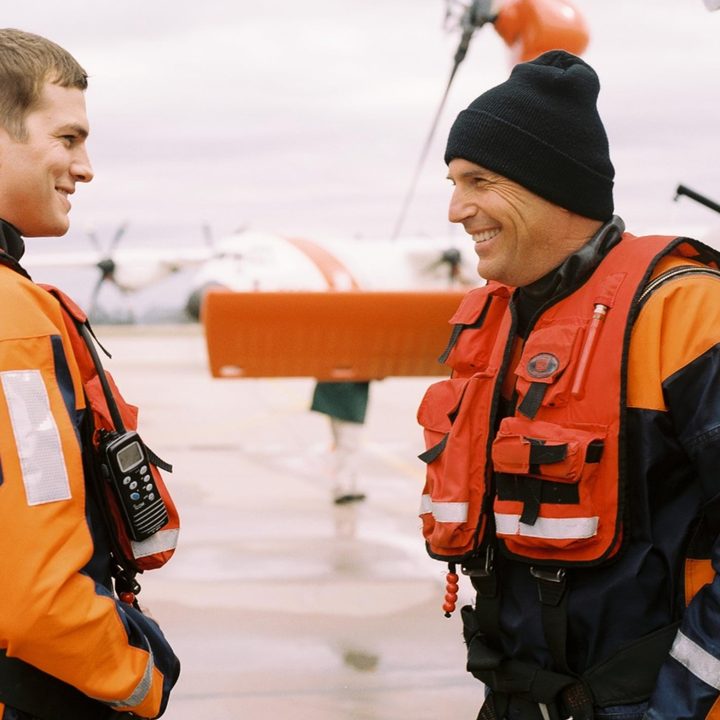Two coast guard swimmers stand in front of each other and converse in The Guardian.